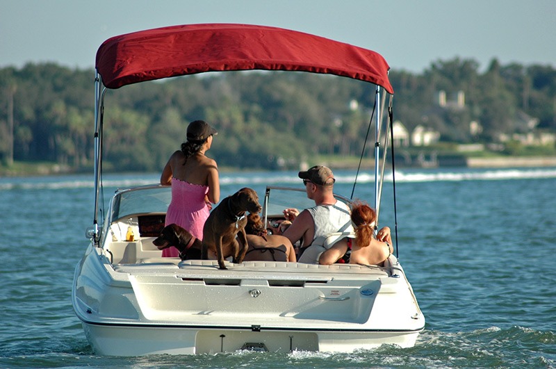 family enjoying time on a lake in a covered boat