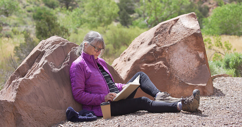 woman leaning on rock reading a book