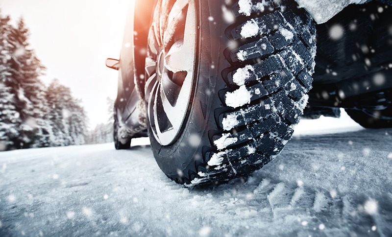 close up of snow tires on a car driving during a winter move to a new home