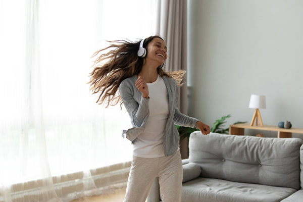 young woman wearing headphones dancing in apartment